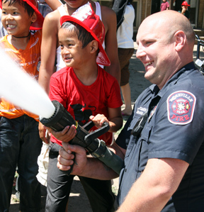 boy and firefighter practicing with hose